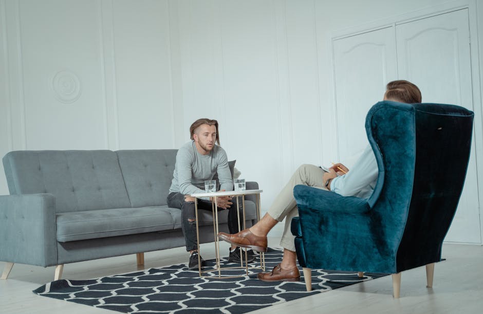 Two men engaged in a therapy session inside a modern office setting, discussing mental health. - Photo by Tima Miroshnichenko on Pexels