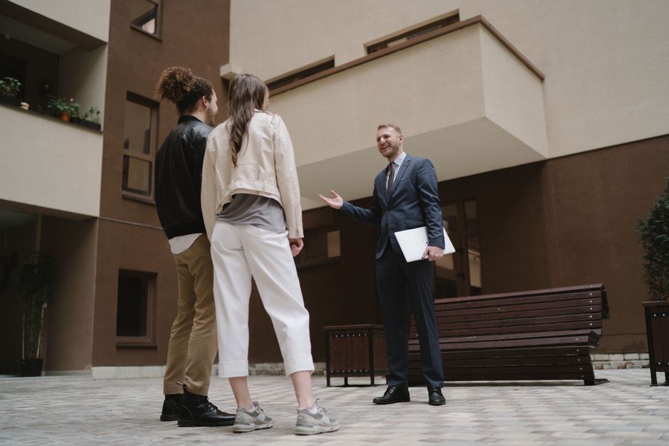 A realtor converses with a couple in a modern apartment courtyard. - Photo by Anastasia Shuraeva on Pexels