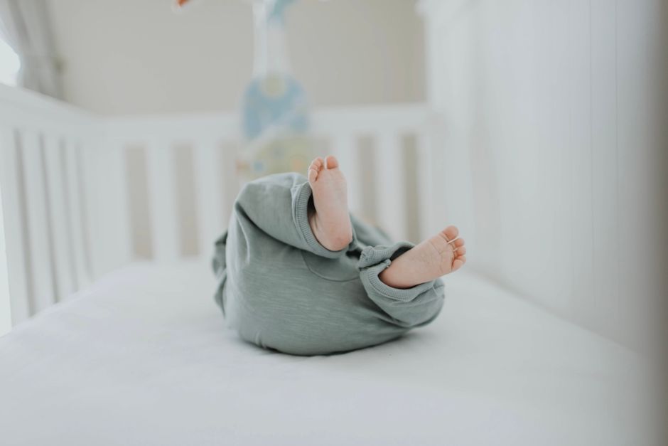 Cute baby feet in pajamas on a soft white crib. Perfect for children's room decor. - Photo by Leah Newhouse on Pexels